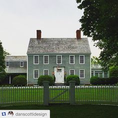 a large gray house sitting next to a lush green field