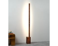 a tall wooden pole next to a white wall with a light on it's side