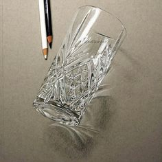 a pencil is laying on top of a glass with an empty cup next to it