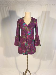 "vintage 1960s long blouse handmade   purple w/pink/green/blue floral print synthetic knit feel- softer, not abrasive or slippery button up front long bell / flounce sleeve open front from waist long enough to be a very mini dress but open flap front would make it best w/leggings or shorts underneath good vintage condition, light wear no size tag, see below measures, lying flat, shoulder-14 1/2\" sleeve-21\" chest-17\" waist-15\" length-31\"     We do not offer returns or refunds unless something is grossly misrepresented. Please contact us within 2 business days of receiving to discuss any possible returns for this reason. We do not offer refunds for your shipping fees. Please feel free to contact us with any questions you may have about an item prior to purchase and we will gladly answer Casual Fitted Blouse With Vintage Print, Fitted Bohemian Blouse With Button Closure, Fitted Bohemian Blouse For Fall, Fitted Cotton Blouse With Retro Print, Hippie Style Long Sleeve Floral Print Blouse, Groovy Long Sleeve Tops For Spring, Fitted Bohemian Patterned Blouse, Hippie Fitted Blouse For Fall, 70s Inspired Fitted Cotton Tops