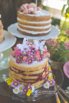 there are three cakes on the table and one is decorated with flowers, butterflies and daisies