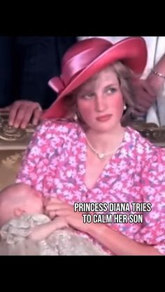 a woman holding a baby wearing a pink hat with words written on the top and bottom