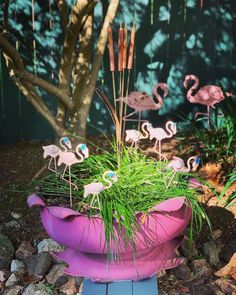 there is a potted plant with flamingos in it and grass growing out of it