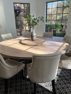 a dining room table with chairs around it and a vase filled with flowers on top