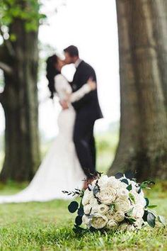 a bride and groom kissing in the park