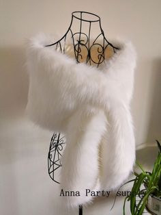 a white fur stole is hanging on a rack next to a potted green plant