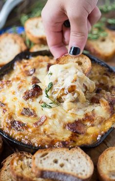 a person dipping some food into a skillet with garlic bread on the side,