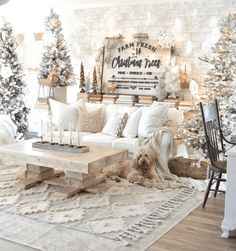 a living room decorated for christmas with white furniture and trees on the wall behind it