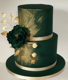 a three tiered green cake with gold trim and a flower on the top layer