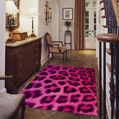 a pink and black area rug on the ground in front of a stair case with a chair