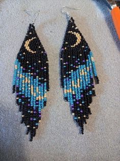 a pair of beaded earrings sitting on top of a table next to a pair of scissors