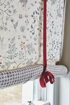 the curtain is tied to the window with a red ribbon around it and hanging in front of a window sill