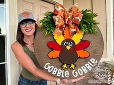 a woman holding up a sign that says gobble gobble with a turkey on it