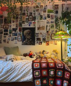 a bedroom with many pictures on the wall and a bed covered in blankets, pillows, and stuffed animals