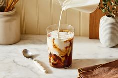 a pitcher pouring milk into a glass filled with ice cream