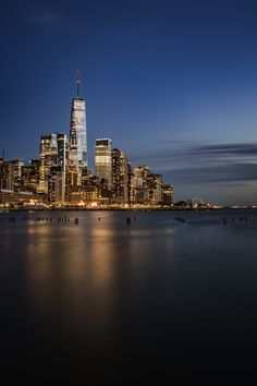 the city skyline is lit up at night, with skyscrapers in the foreground