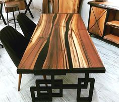 a wooden table sitting on top of a hard wood floor next to two black chairs