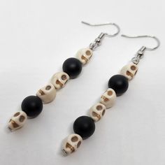 This is a pair of drop earrings. Each earring features 4 skull shaped beads made from howlite and 2 natural black agate beads. The ear hooks are stainless steel and will include 2 transparent rubber tube backs. The black agate beads are 8mm across with a matt/frosted finish. The beaded portion of the earring is 48mm long. These earrings are handmade, by me, and are made to order. It's recommended that you remove these earring before swimming or showering. Nickel Free Black Skull Earrings, Adjustable Black Skull Earrings, Handmade Black Skull Earrings, Adjustable Black Skull-shaped Earrings, Diy Earrings Easy, Diy Kandi, Black Agate, Skull Earrings, Halloween Earrings