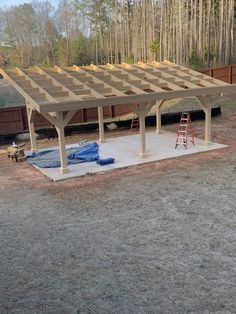 a large wooden structure in the middle of a yard with tools on top of it