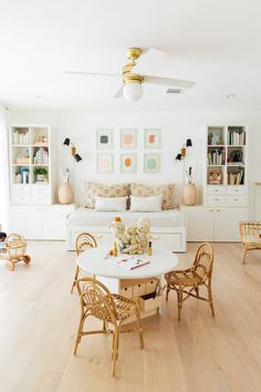 a living room filled with furniture and a white table surrounded by wooden chairs on top of hard wood flooring