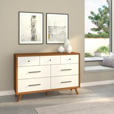 a white dresser sitting next to a window in a room with two pictures on the wall