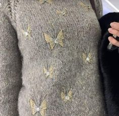 a woman wearing a sweater with butterflies on it