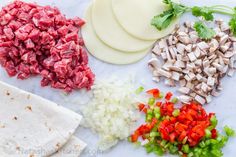 chopped up vegetables and meat on a white counter with tortilla wrappers next to them