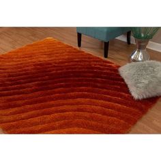 an orange area rug on the floor with a vase and chair in the back ground