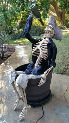 a skeleton sitting in a tub with a hat on it's head and arms