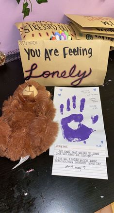 a teddy bear sitting on top of a table next to a sign and handprint