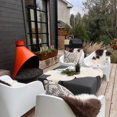 two white chairs sitting on top of a wooden deck next to a black and white couch