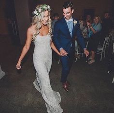 a bride and groom are walking down the aisle at their wedding reception with guests in the background