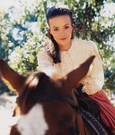 a woman sitting on top of a brown and white horse