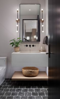 a bathroom with a sink, mirror and potted plant on the counter in front of it