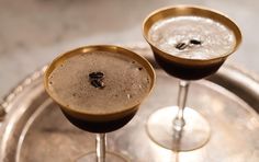 two champagne glasses sitting next to each other on top of a metal tray with silver rims