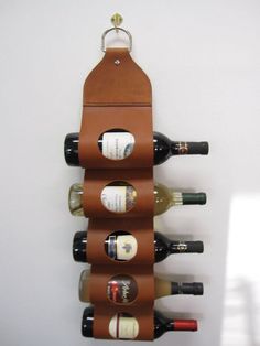 a leather wine holder with six bottles of wine in it, hanging on the wall