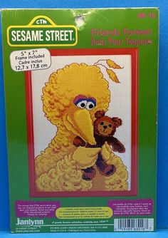 the sesame street cross stitch pattern is on display in front of a wooden shelf with an orange teddy bear