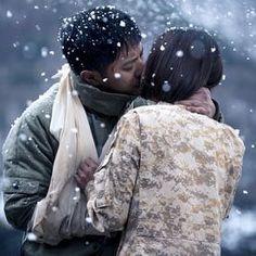 two people standing in the snow with their arms around each other