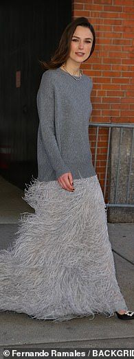 a woman in a gray dress is standing on the sidewalk