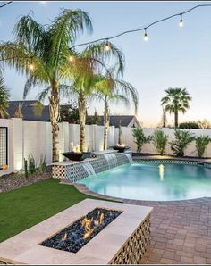 a backyard with a pool, fire pit and palm trees in the back yard at dusk