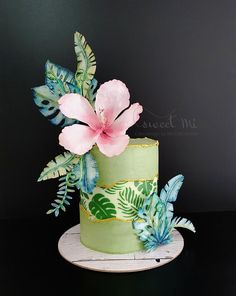 a green cake with pink flowers and leaves on it