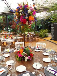 a table set with plates, silverware and flowers in a tented area for an event