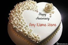 a white heart shaped cake with flowers on it that says happy anniversary any name here