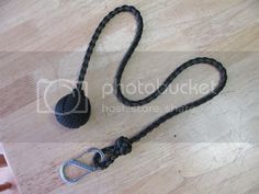 a black rope with a ball on it sitting on a wooden table next to a pair of scissors