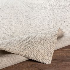 a close up view of the fabric on a rug with wood flooring in the background