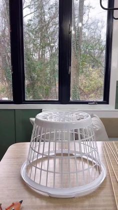 a white birdcage sitting on top of a wooden table next to a window