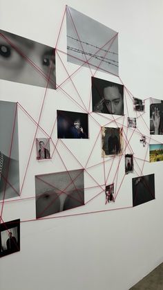 a white wall with many pictures on it and red string attached to the wall next to it