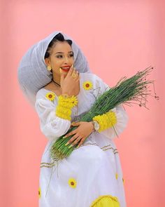 a woman in a white dress and yellow flowers is posing for the camera with her hand on her face