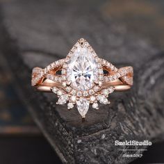 an engagement ring with a pear shaped center surrounded by round brilliant cut diamonds on a rock