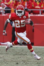 a football player running with the ball in his hand and people watching from behind him